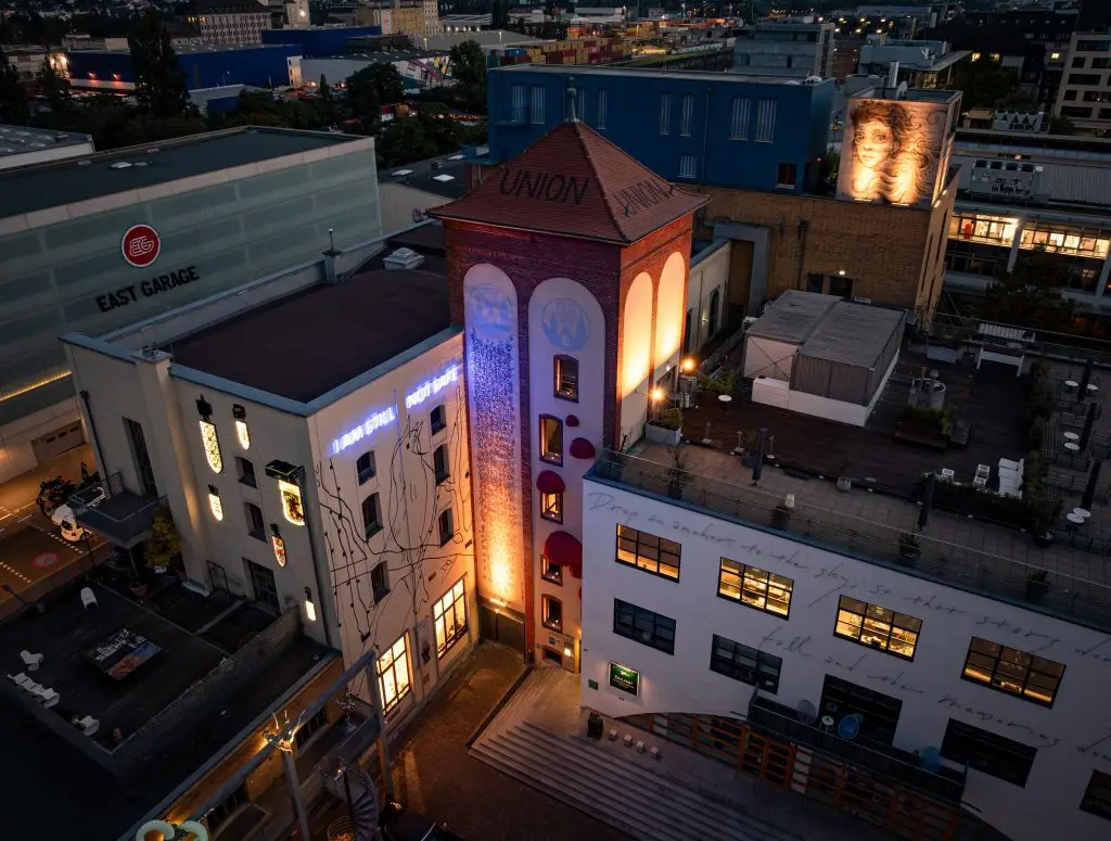 Blick von oben auf den Union-Turm und umliegende Gebäude bei Nacht, mit beleuchteten Fenstern und urbaner Dachlandschaft.