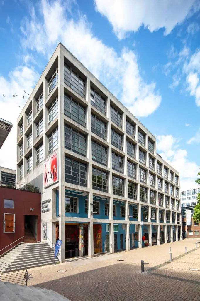 Betonraster-Fassade mit Kunstbanner und Schriftzug „Baumarten sterben angenehm“ am Gebäude des Union-Geländes.