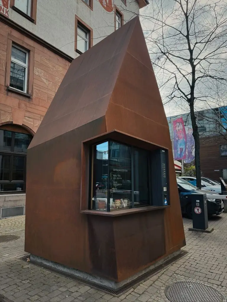 Rostbraunes Cortenstahl-Häuschen mit spitzem Dach und Fenster auf dem Union-Gelände Frankfurt.
