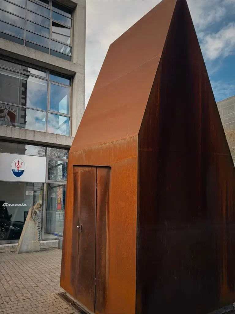 Rückseite des spitzen Cortenstahl-Häuschens mit nahtlos integrierter Tür, Frankfurter Union-Gelände.