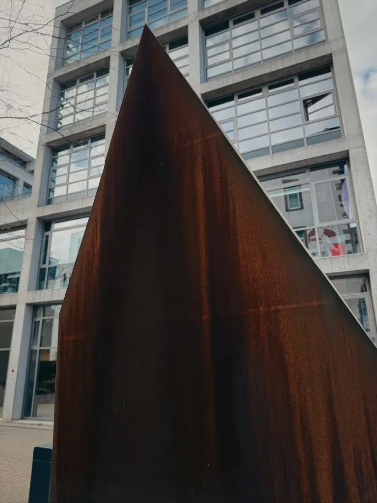 Nahaufnahme der spitz zulaufenden, rostigen Dachkonstruktion vor moderner Fassade, Union-Gelände.