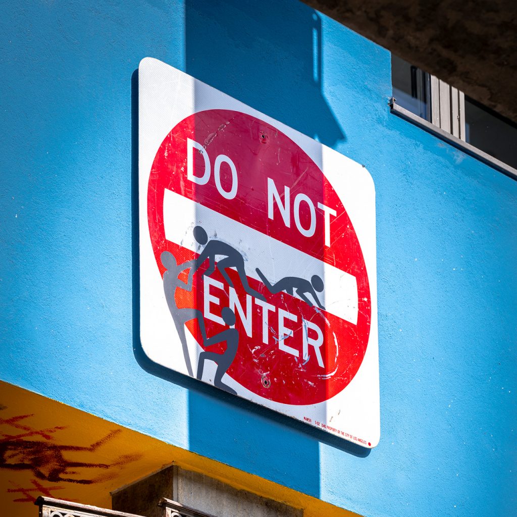 Verfremdetes "DO NOT ENTER"-Schild mit aufgemalten Strichmännchen an einer blauen Wand, Union-Gelände Frankfurt.
