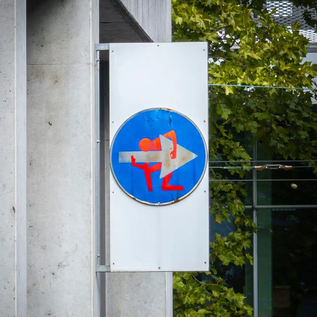Street-Art-Schild: Ein rotes Strichmännchen trägt einen weißen Pfeil. Gesehen auf dem Frankfurter Union-Gelände.