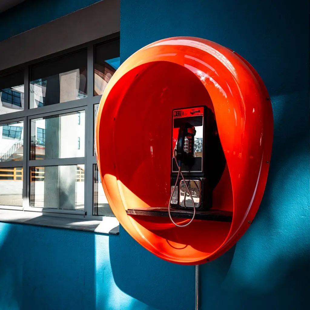 Orangefarbene Retro-Telefonhaube an einer blauen Fassade auf dem Frankfurter Union-Gelände