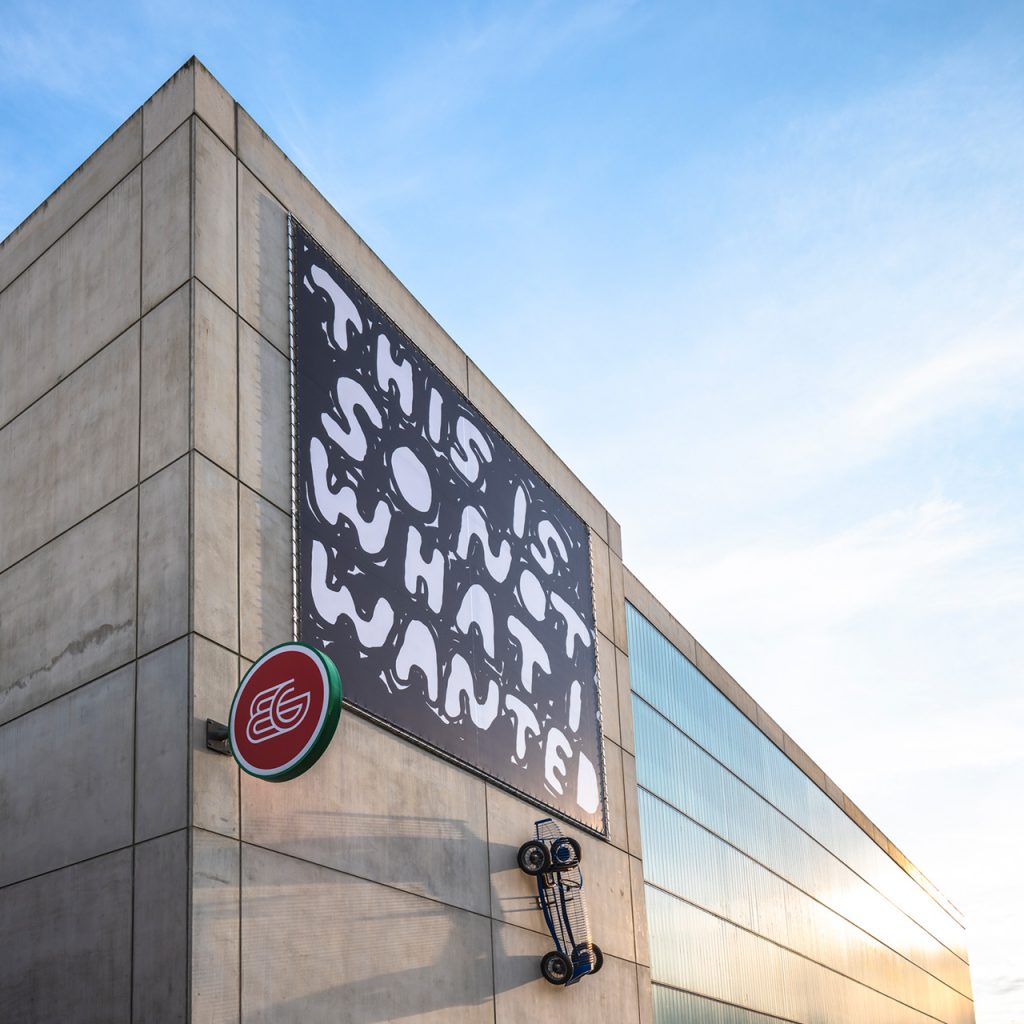 Kunstwerk von Stefan Marx mit 'THIS IS SO NOT WHAT I WANTED' Banner und Sportwagen-Skulptur, Weitwinkel.