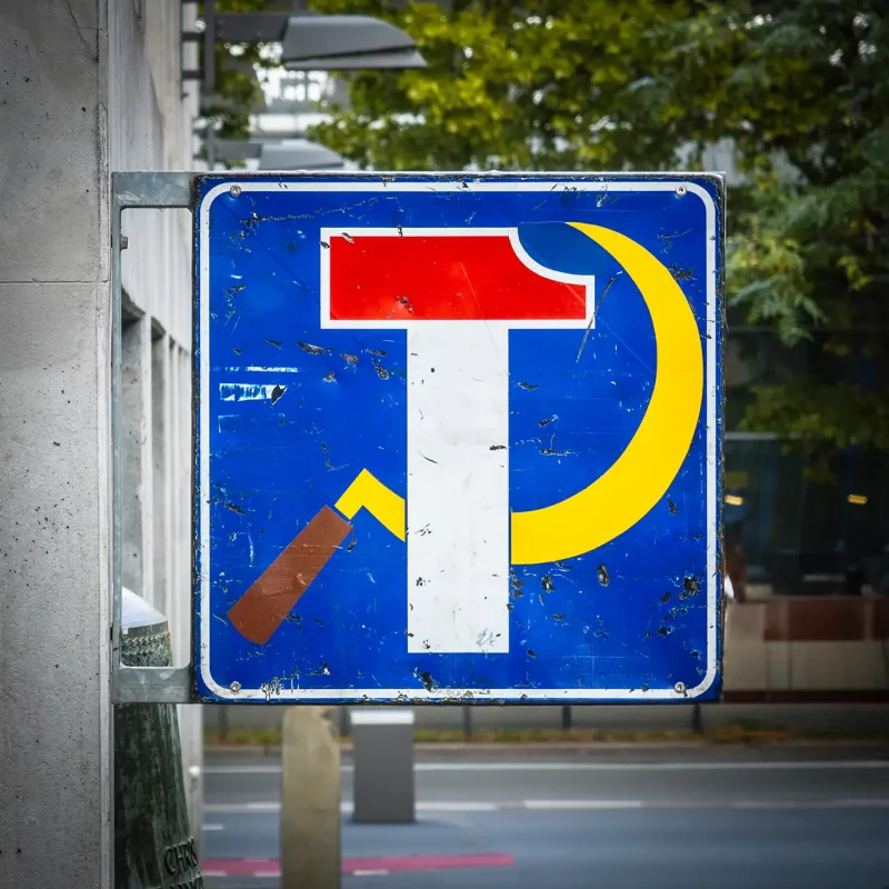 Nahaufnahme des blauen Straßenschildes mit stilisiertem Hammer, Sichel und "T" auf dem Frankfurter Union-Gelände.