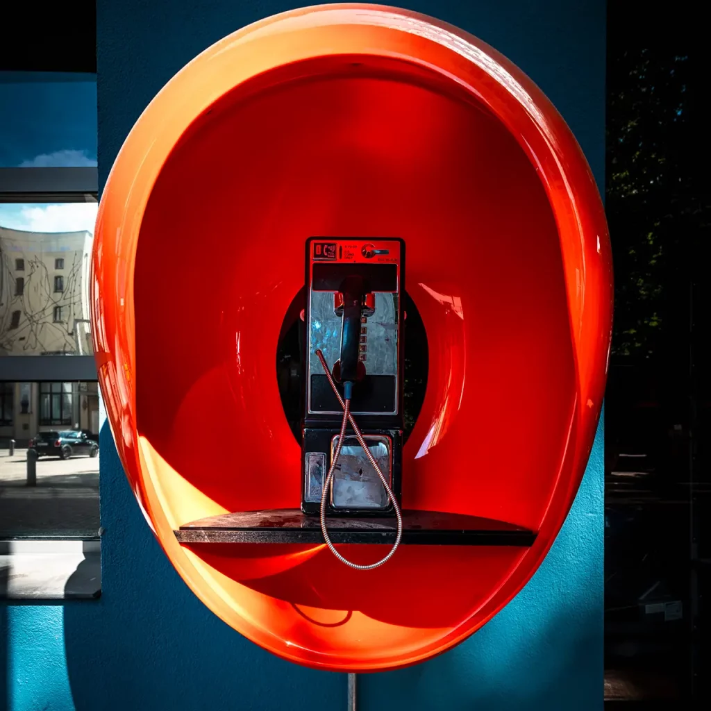 Nahaufnahme eines Retro-Münztelefons in einer leuchtend orangen Haube auf dem Frankfurter Union-Gelände